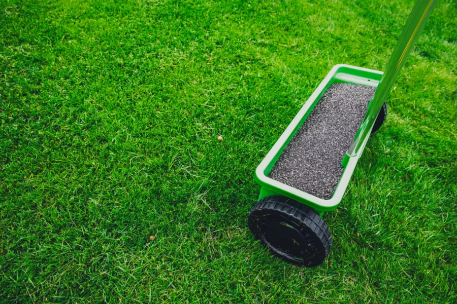Green grass with a push cart with grass seed in it